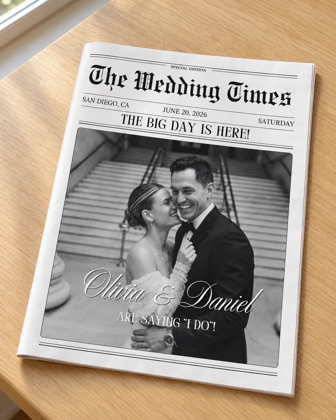 Mockup of a folded black and white wedding newspaper, The Wedding Times, with the couple's photo on the front page, lying on a wooden table