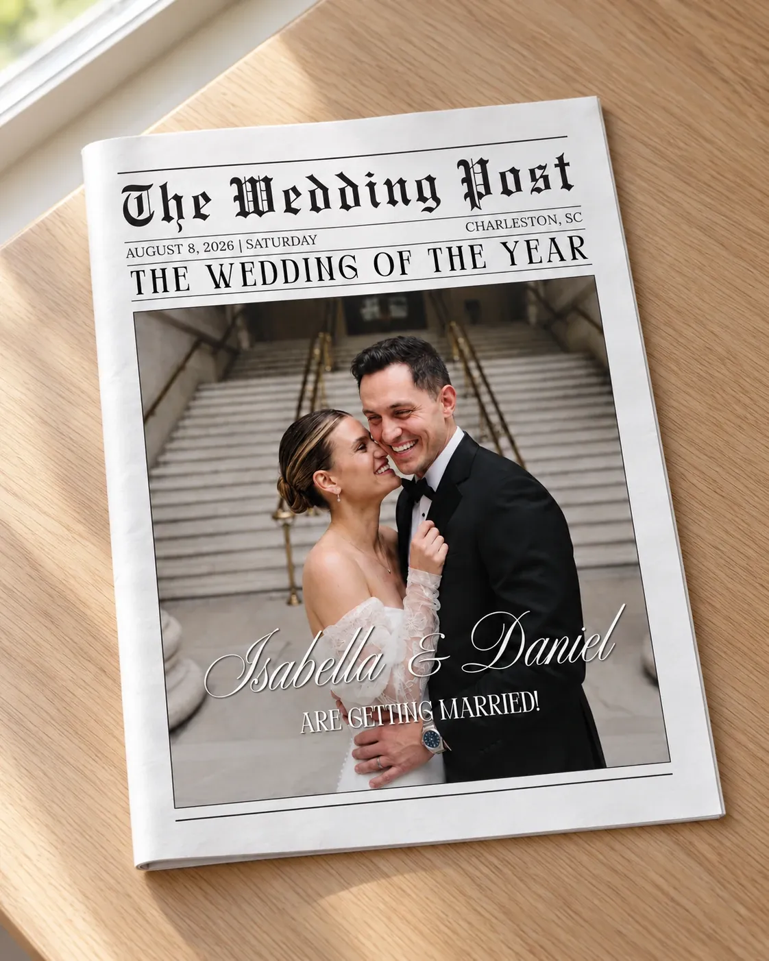 Mockup of a folded color wedding newspaper, The Wedding Post, with the couple's color photo on the front page, lying on a wooden table